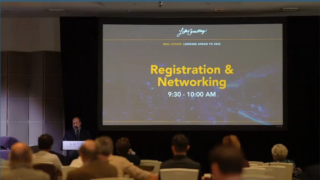 LED display screen at real estate networking event showing registration schedule