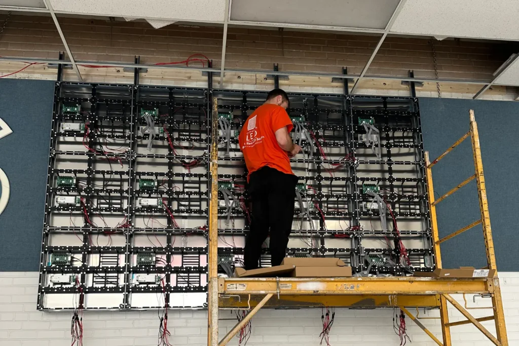Technician installing indoor LED video wall panels on a large frame