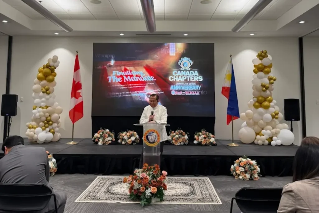 Canadian LED at Canada Chapters anniversary event with speaker on stage, Canadian and Philippine flags, balloons, and floral decorations.
