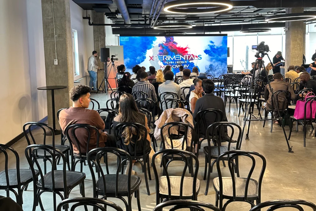 People seated in front of a bright Canadian LED video wall during the Xperimentals event in a modern indoor venue.